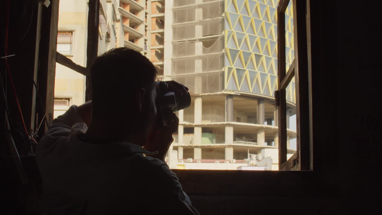 Man Capturing Facade of Building under Construction from Window