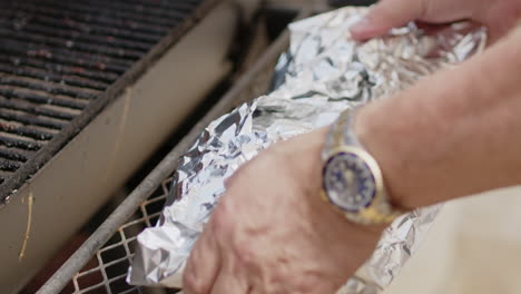 Man-foil-wrapping-BBQ-pork-ribs-and-placing-them-on-hit-pit-smoker-with-chicken-thighs