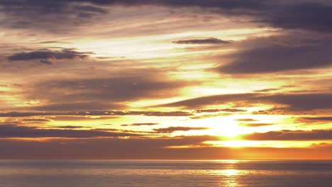 golden sunrise over ocean timelapse with clouds moving in dawn skies, wide shot