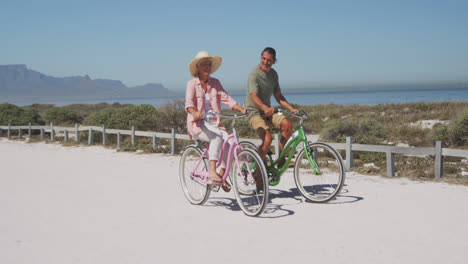 Älteres-Kaukasisches-Paar,-Das-Fahrrad-Am-Strand-Fährt