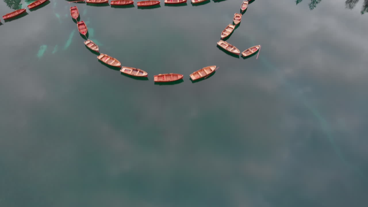 toma aérea hacia atrás desde un dron que revela botes alineados en el lago braies en los dolomitas, italia