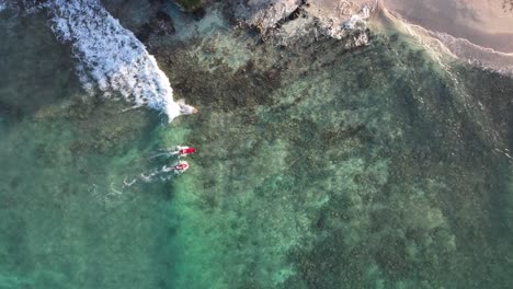 aerial drone chasing surfers to beach on mokulua islands in paradise panning up to entire island and reefs clear water at sunrise with beautiful water surrounding