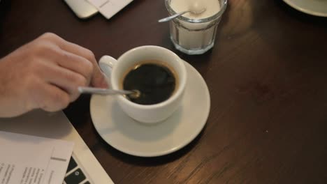 male freelancer adding sugar to coffee