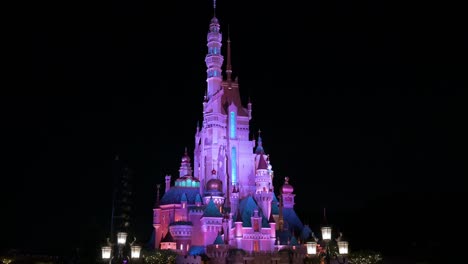 nighttime view of the iconic disney castle is seen in the background at the american amusement park disneyland resort park in hong kong