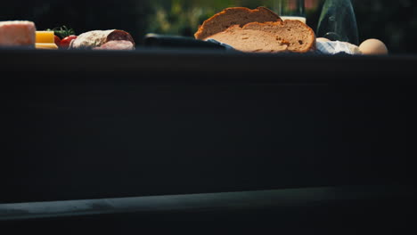 image moving up revealing a garden table showcasing an assortment of mouthwatering snacks including salami, cheese, and bread. great for food vlogs, recipe videos, and appetizing product presentations