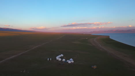 aerial view of yurts along the shore of picturesque lake song-kul in kyrgyzstan at sunset