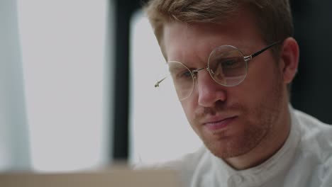 programador o especialista en informática está trabajando con una computadora portátil en la oficina, retrato en primer plano de un hombre guapo con gafas
