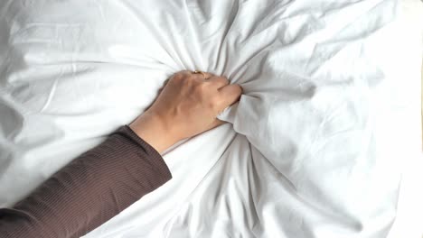 woman's hand touching a white pillow