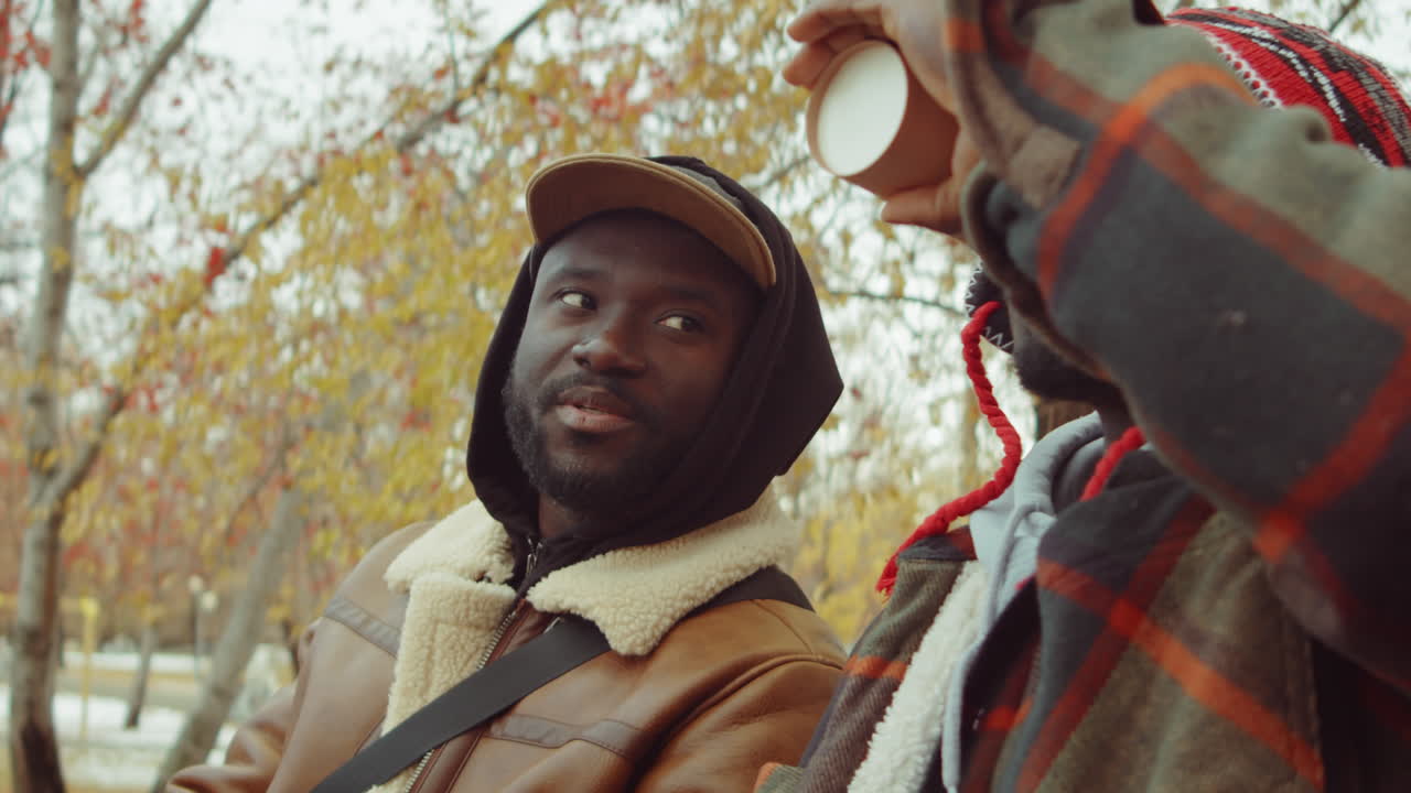 아프리카계 미국인 친구 들 이 공원 의 벤치 에서 커피 를 마시고 대화 하고 있다