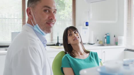 Portrait-of-smiling-caucasian-male-dentist-with-female-patient-at-modern-dental-clinic