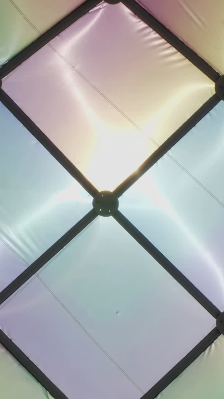 Video verticale: Telecamera in movimento che rivela la griglia del soffitto di una tenda, mostrando nervature viola e oro che cambiano