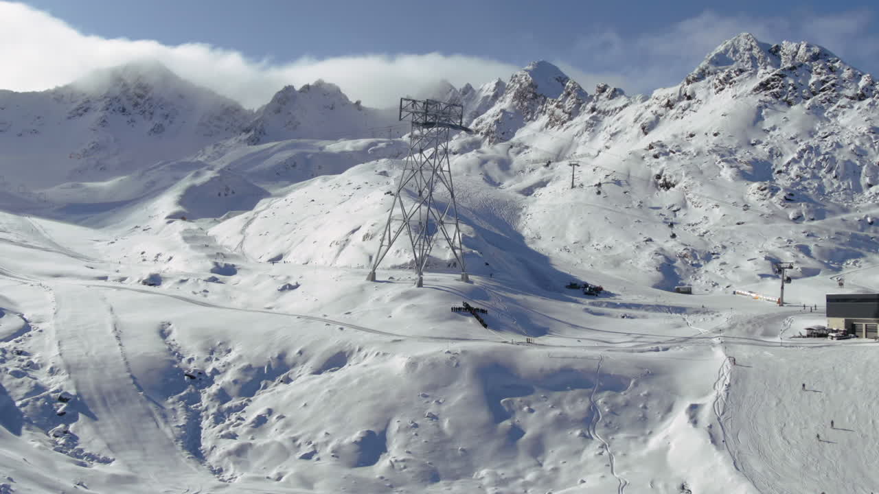 panorama aéreo de movimiento hacia adelante de la zona de esquí en kauntertal austria con cruz cristiana de personas en la ladera de la montaña con esquiador durante la temporada de invierno
