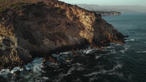 Eine-Luftaufnahme-Der-Point-Dume-Cliffs-In-Malibu-In-Kalifornien,-Während-Die-Wellen-Abends-Bei-Sonnenuntergang-Gegen-Die-Felsen-Schlagen