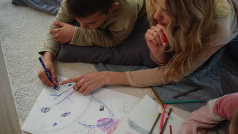 madre e hijos haciendo arte en casa. madre e hijos acostando alfombra con cuaderno de bocetos