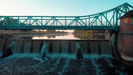 a small dam with metal and brick bridge in poland at sunrise