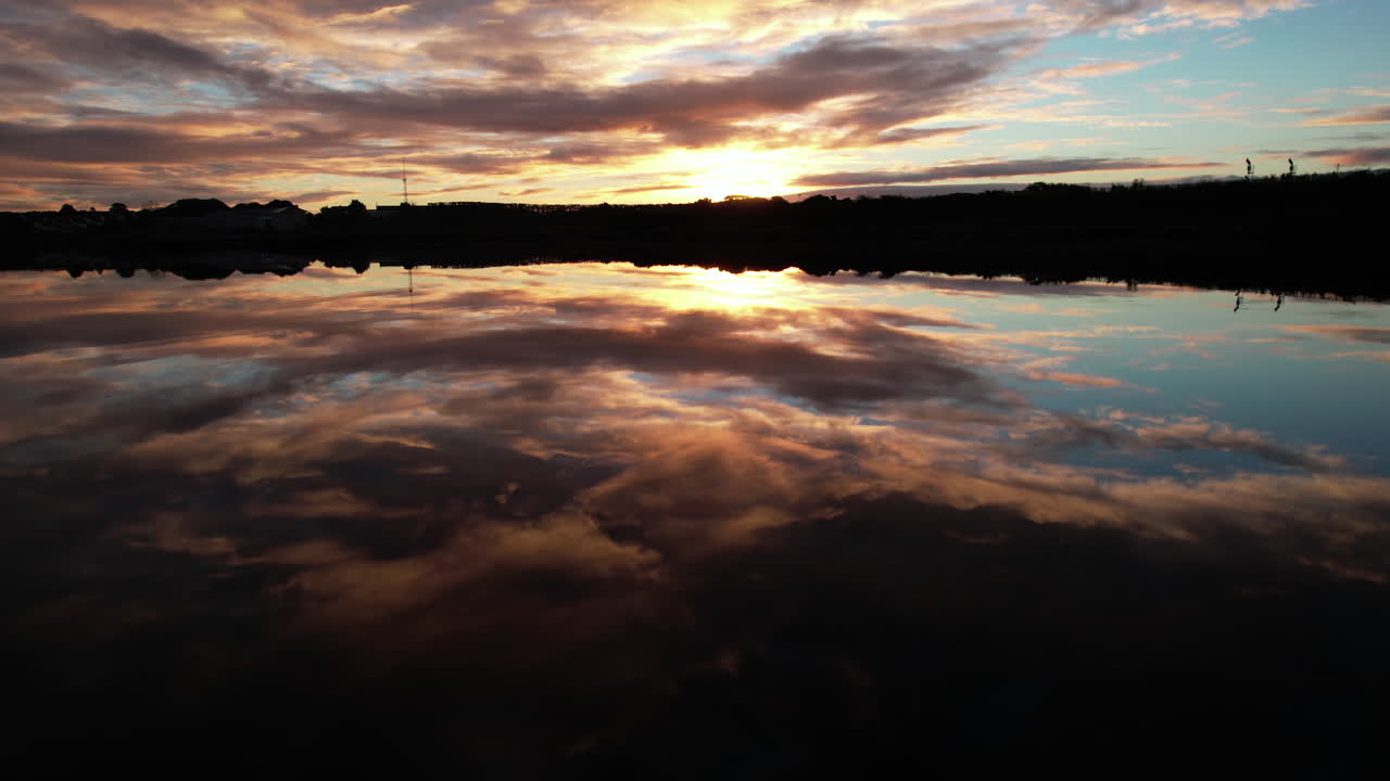 Flying above water with amazing sunrise sky mirror reflection, drone aerial view of bay in Galway, Ireland