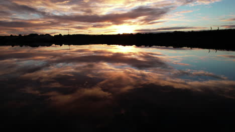 volando sobre el agua con un increíble reflejo del espejo del cielo del amanecer, vista aérea de drones de la bahía en galway, irlanda