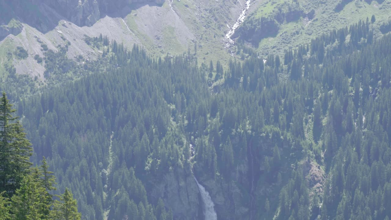 cascada de staubifall en medio de un denso bosque con cordilleras rocosas en el fondo en el cantón de uri en unterschachen, suiza