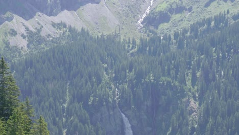 staubifall waterfall amidst dense forest with rocky mountain ridges at background in the canton of uri in unterschachen, switzerland