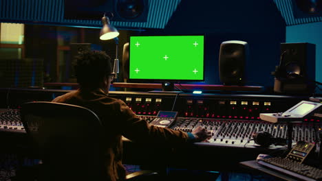 productor de música afroamericano trabajando con pantalla verde en la pc