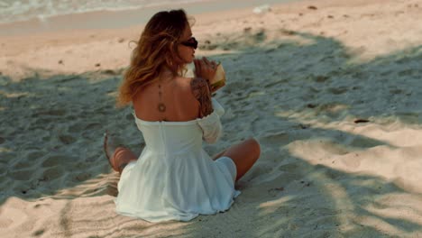 woman drinking coconut on the beach