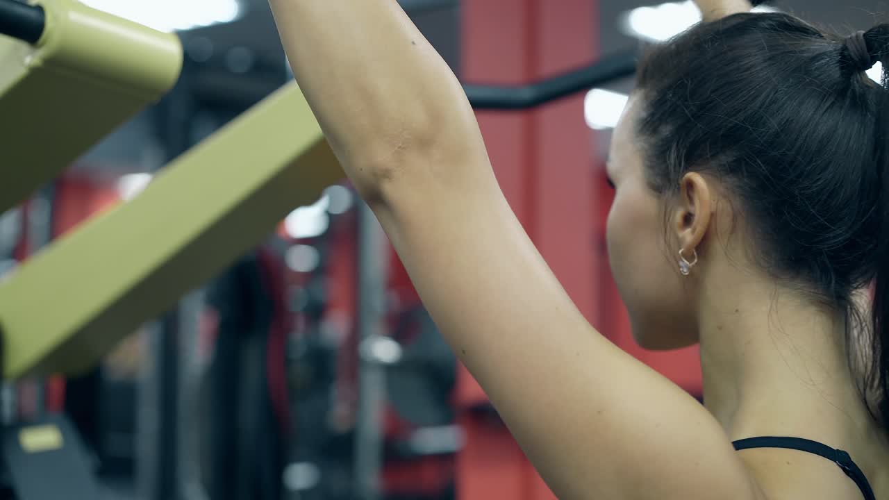 una mujer joven de espalda cerrada hace ejercicio en un soporte de mango