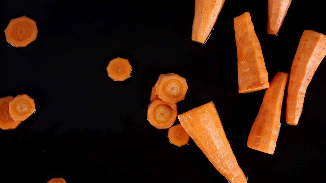 Pezzi di carota fresca che cadono in acqua