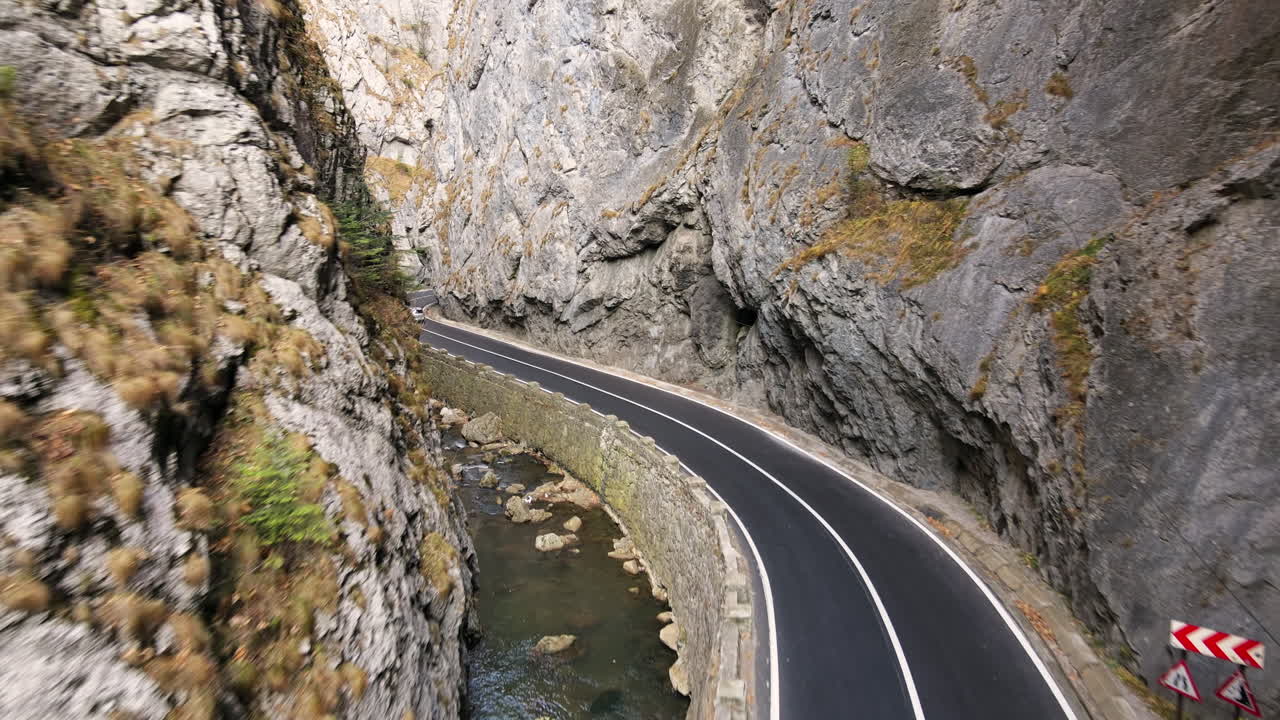 Aerial drone view of nature in Romania. Carpathian mountains, road with cars in the valley, rocky cliffs, river