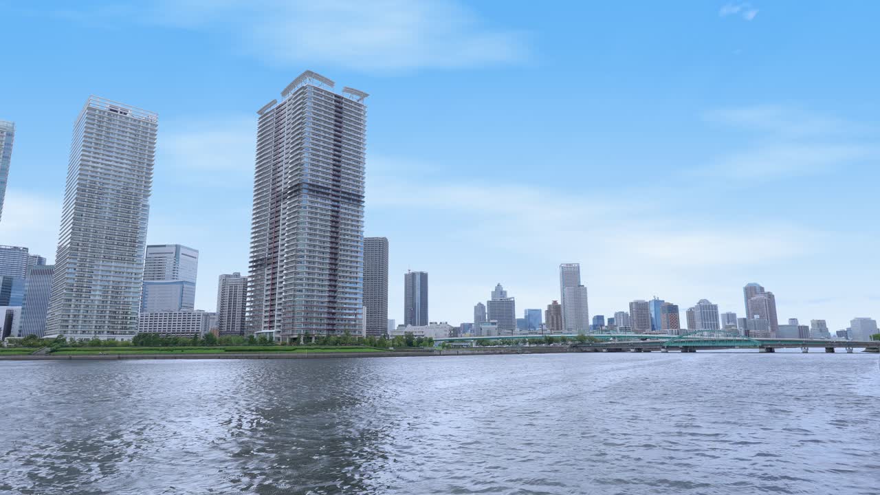 A wide, peaceful shot of the expansive Tokyo Bay with the distant cityscape and a bright sky