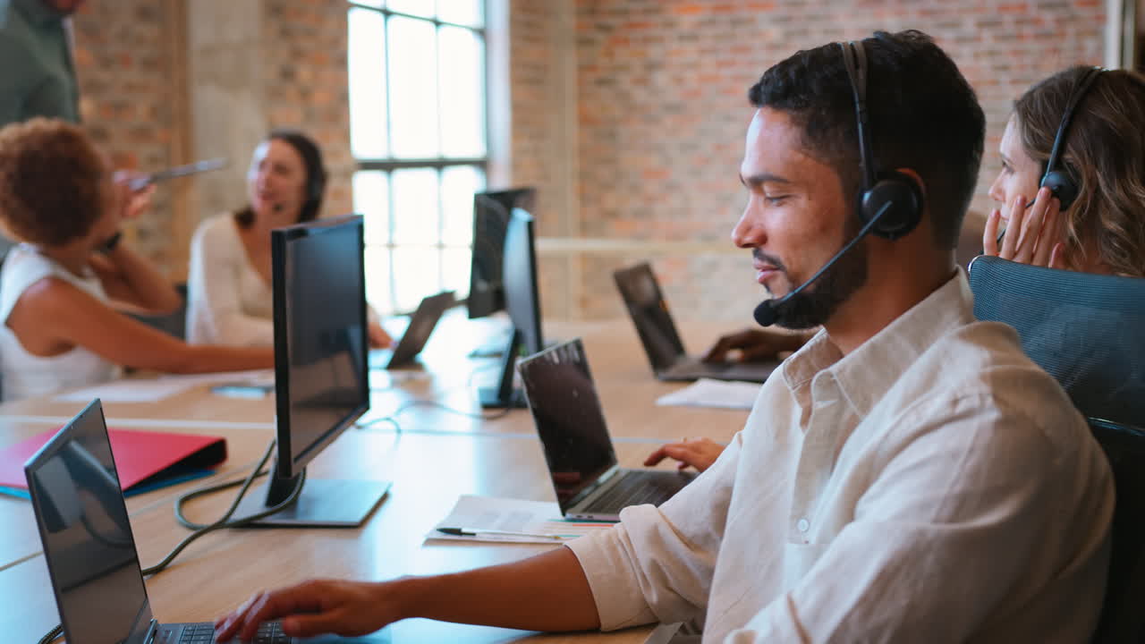 Multi-Cultural Business Team Wearing Headsets Working In Customer Support Centre