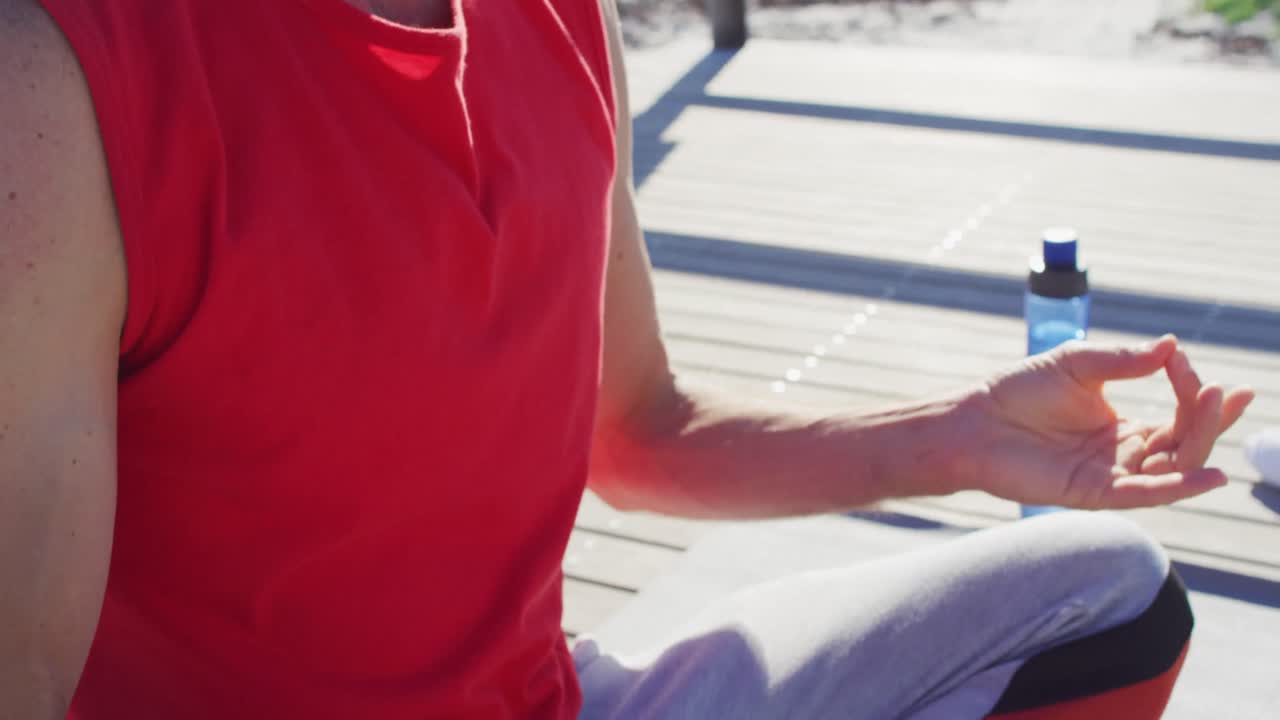 video de la sección media de un hombre caucásico practicando meditación de yoga sentado al sol