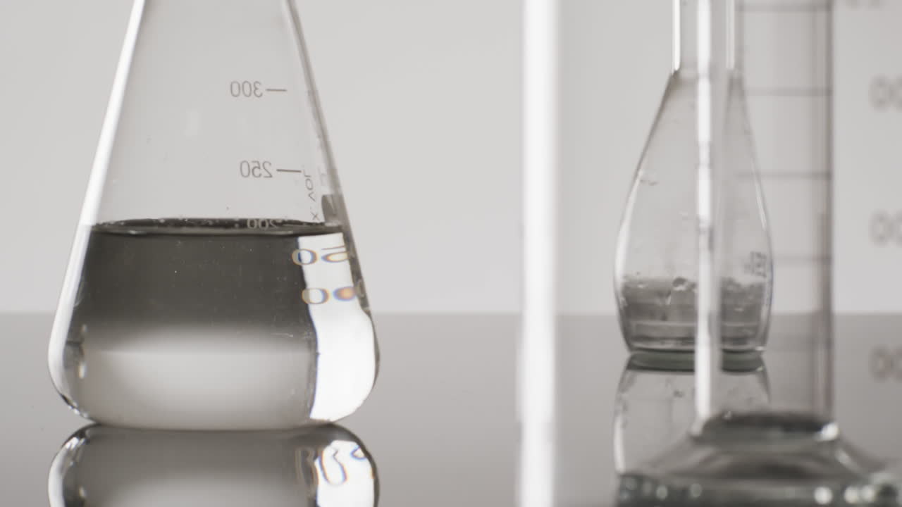 Video of close up of glass laboratory beakers and dishes with copy space on white background