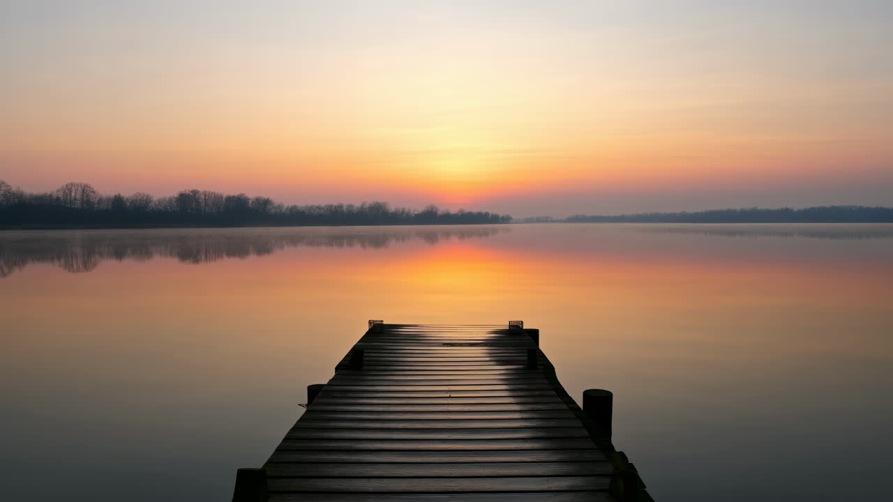 Serene Lake with Wooden Pier Reflecting Golden Sunrise