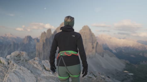 female mountaineer walking in front of the famous three peaks - tre cime