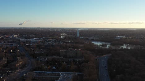 Una-Vista-Aérea-De-Un-Barrio-Suburbano-En-Long-Island-Justo-Antes-Del-Atardecer,-Lo-Suficientemente-Alto-Como-Para-Ver-El-Horizonte,-Un-Largo-Camino-Y-Un-Lago