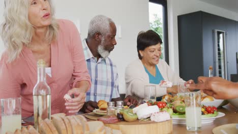 happy senior diverse people having dinner at retirement home