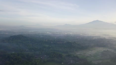 Aerial-view-showing-overcast-morning-landscape-with-mountains-in-background-in-Asia