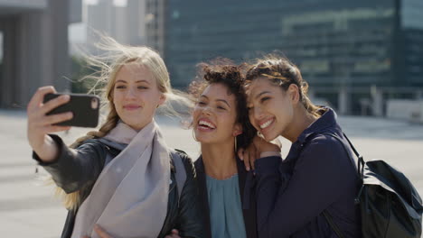 Retrato-Hermosas-Amigas-Multiétnicas-Usando-Un-Teléfono-Inteligente-Tomando-Una-Foto-Selfie-Juntas-En-La-Ciudad-Disfrutando-De-Un-Cálido-Día-Soleado-Compartiendo-Experiencias-De-Viaje-Urbano-En-La-Tecnología-De-La-Cámara-Del-Teléfono-Móvil-En-Cámara-Lenta