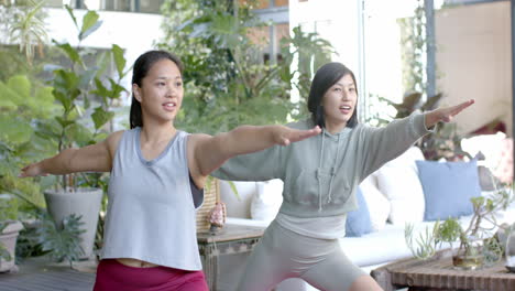 Happy-asian-female-friends-practicing-yoga-on-sunny-terrace,-slow-motion