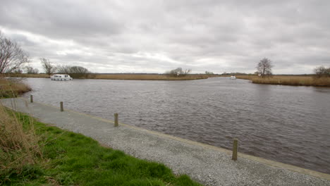 extra wide shot of the river bure with a white norfolk broads cruisers boat passing the entry to south walsham broad