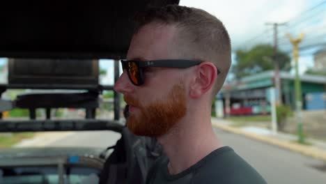 a close up shot of a man having blonde beard taking a ride of a vehicle for travelling