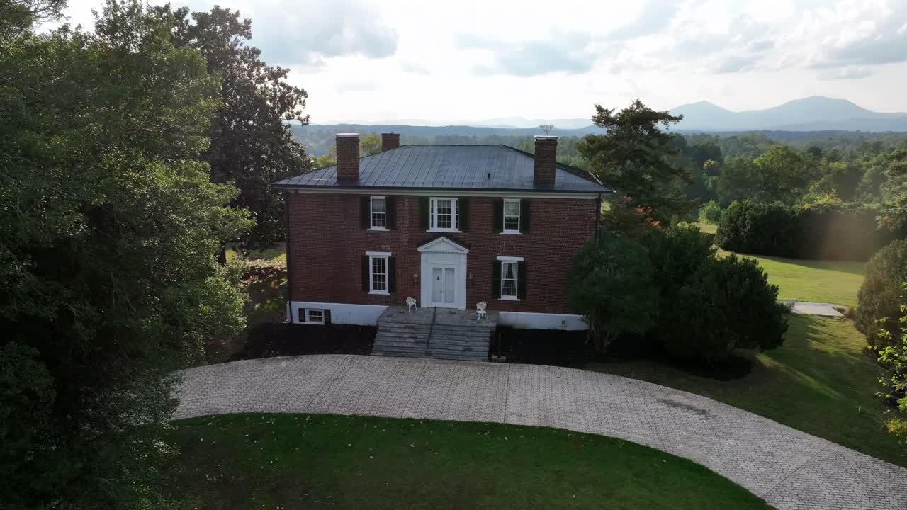 Aerial view of American building. With red brick and four chimneys on roof. Sunny summer day in rural suburb town of USA. Approaching shot