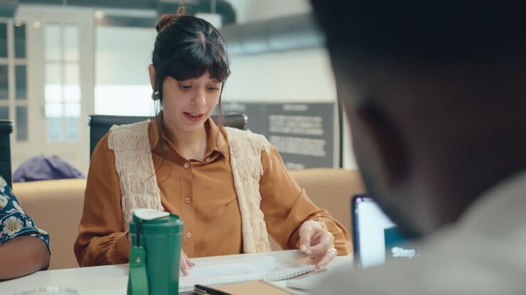 giovane donna d'affari che discute di documenti con un collega in una riunione d'ufficio