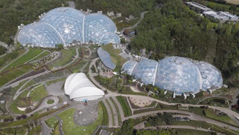 high-altitude view of eden project geodesic domes gleaming amid concentric botanical zones and wooded quarry slopes, emphasising innovative biomes and environmental stewardship