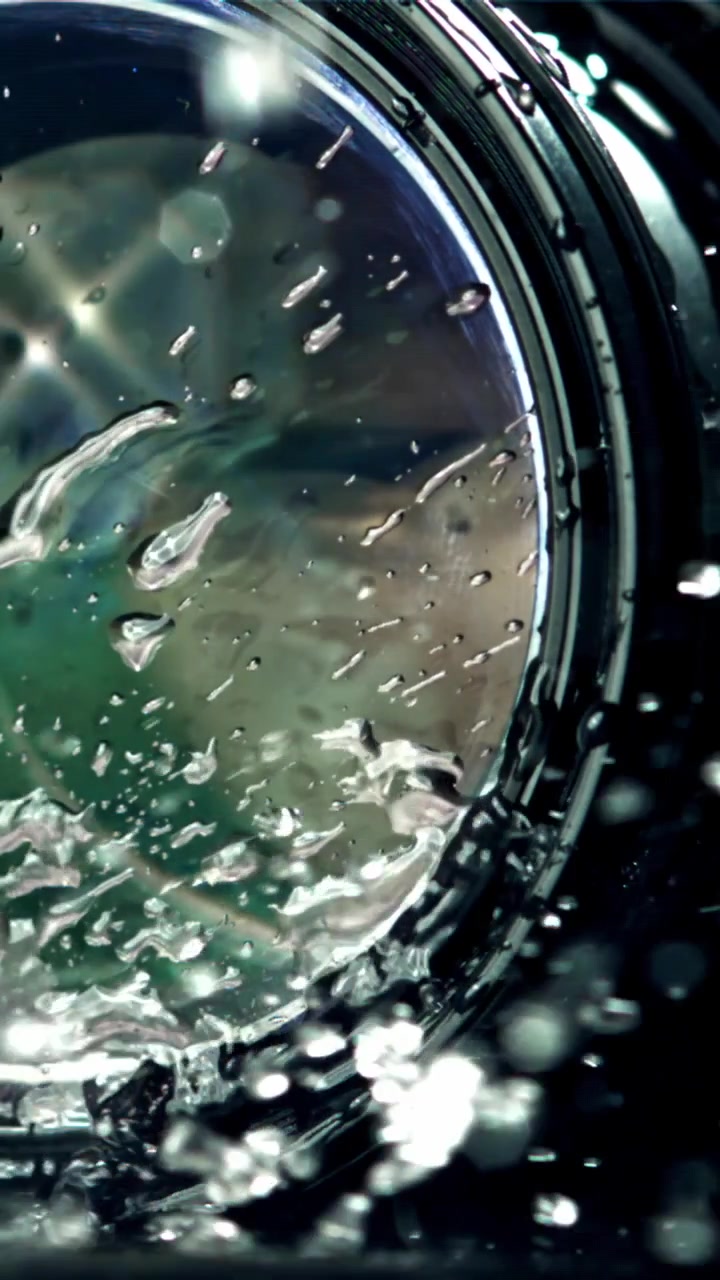 Macro di gocce d'acqua che schizzano su una lente di vetro.