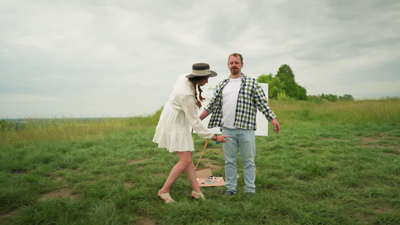 A woman in a stylish hat and white dress sprays mosquito repellent on a man s body in a grassy field. The man, dressed in a checkered shirt, stands calmly with his arms outstretched as she sprays him