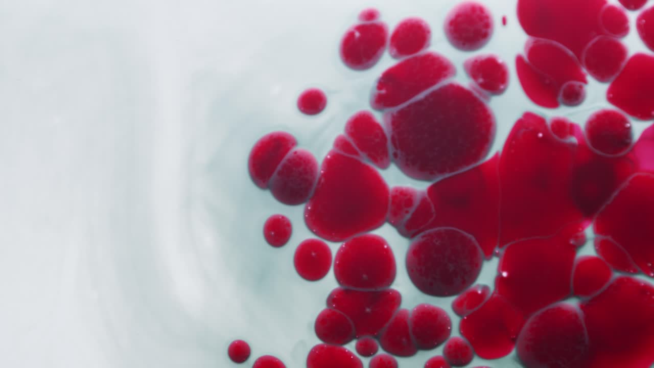 líquido aceitoso rojo cae en líquido blanco y se expande en burbujas, abstracto
