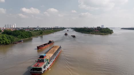 cargo vessels travelling along red river, hanoi city, vietnam