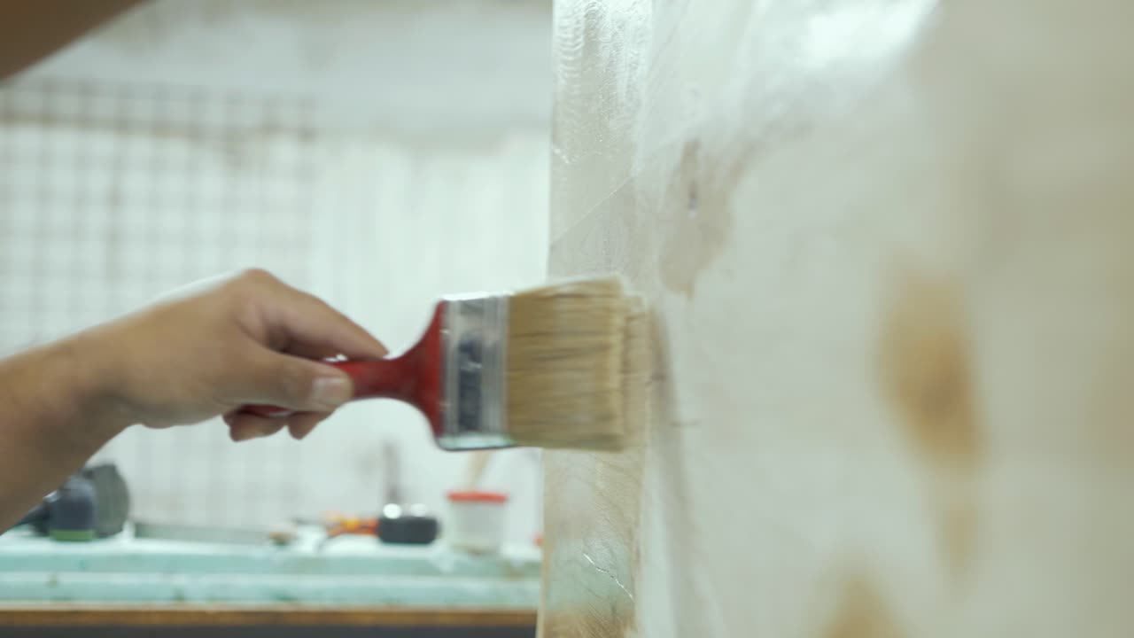 Brushing on clear varnish finishing oak tabletop. Rack focus shot