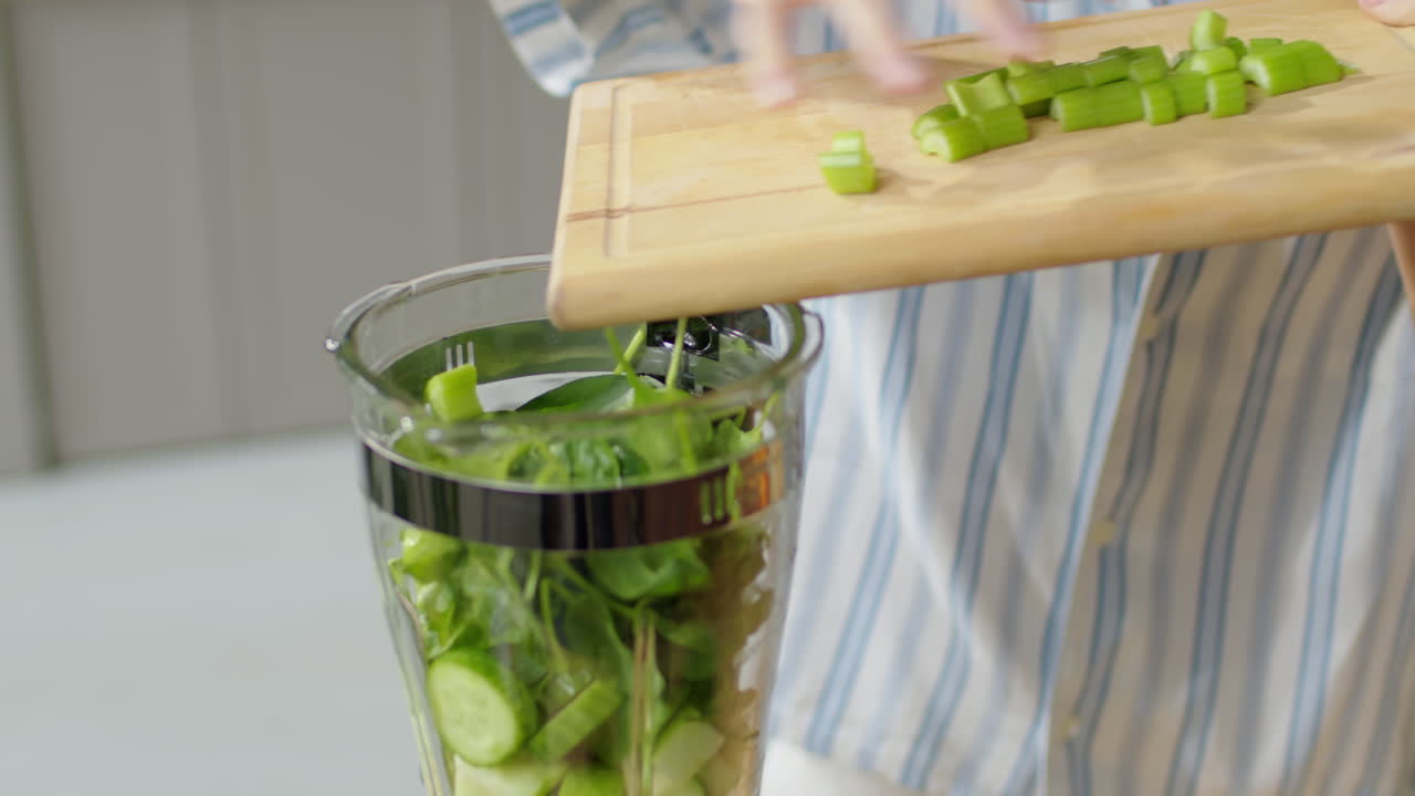 Woman Adding Celery to Blender